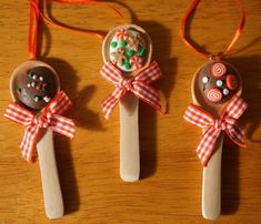 three wooden spoons decorated with candies and lollipops are on a table