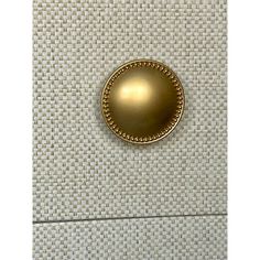 a close up of a gold button on a white wall