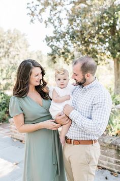 a man and woman holding a baby in their arms while standing next to each other