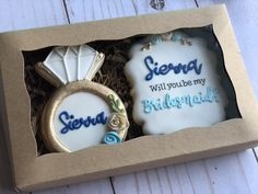 two decorated cookies in a box with the words sierra will you be my bridesmaid?