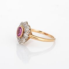 Stylish antique Edwardian pink sapphire & diamond cluster ring crafted in 14k yellow gold (circa 1900s to 1910s). One centre set pink sapphire is estimated at 0.50 carats, accented with eight estimated 0.15 carat old mine cut diamonds. The total diamond weight is estimated at 1.20 carats (estimated at I-J and SI1-I1 clarity). The sapphire is in very good condition and free of cracks or crisps.   The classic cluster design highlights a halo of diamonds surrounding the vibrant and lively pink sapp Old Cut Diamond Ring, Classic Pink Cluster Ring For Formal Occasions, Classic Pink Cluster Ring With Halo Setting, Classic Pink Cluster Ring With Prong Setting, Classic Pink Sapphire Ring With Rose Cut Diamonds, Classic Pink Cluster Ring With Center Stone, Heirloom Pink Round Diamond Ring, Classic Pink Diamond Cluster Ring, Classic Pink Cluster Ring For Anniversary