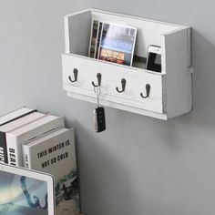 a white shelf with two cell phones and books on it next to a laptop computer