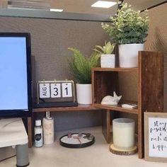 a desk with a computer monitor, calendars and potted plants on top of it