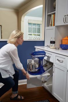 a woman is opening the oven door to look at something on the counter in front of her