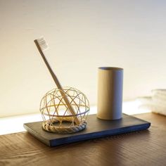 a toothbrush holder on a table next to a cup with a tooth brush in it