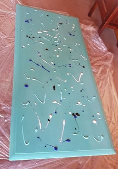 the table is covered in plastic and has blue paint on it's surface with black spots