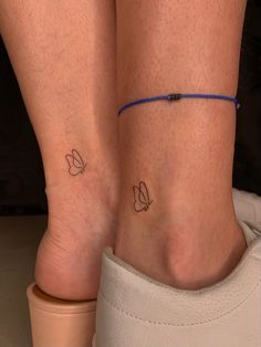 two people with tattoos on their legs and one has a blue string around the ankle