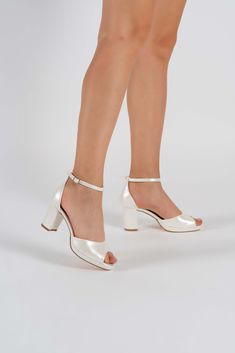 a woman's legs wearing high heeled white shoes with gold straps and heels