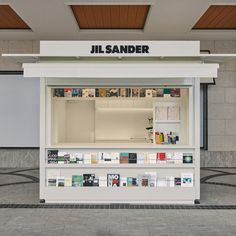 a white display case with books on the front and shelves below it that says jil sander