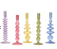 six different colored candles are lined up in a row on a white background with the same color as each candle holder