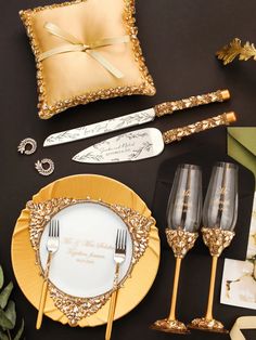 the table is set with gold and white plates, silverware, napkins, and place settings