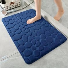 a person standing on a blue mat in front of a bathtub with their feet propped up