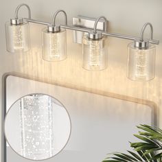 a bathroom vanity with three lights and a mirror on the wall next to a potted plant