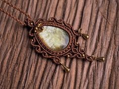 a brown necklace with a large stone in the center on a wooden surface and beads around it