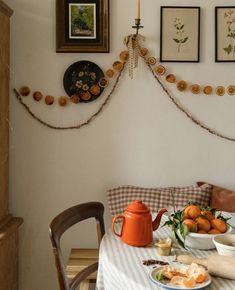 a dining room table with plates, cups and bowls on it next to pictures hanging on the wall