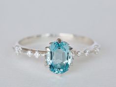 an oval cut blue topazte ring with white diamonds on the band and side stones