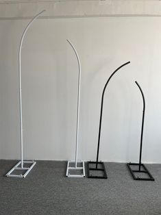 three black and white metal stands on carpeted floor with one standing in front of the other