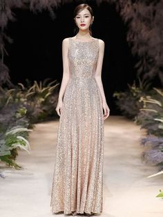 a model walks down the runway wearing a gold gown with sequins on it