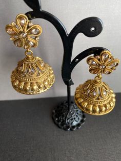 These gorgeous Antique gold plated Jhumka Dangly Earrings are set in white glass stones. Earring length 2.5 inches. Earring width: 1.25 inches. Cheap Gold Dangle Jhumkas, Festive Gold Jhumkas With Intricate Design, Gold Jhumkas With Intricate Design For Festive Occasions, Heavy Brass Bollywood Bridal Earrings, Heavy Chandbali Earrings In Brass, Heavy Chandbali Brass Earrings, Heavy Bollywood Brass Bridal Earrings, Gold Jhumkas With Tilla For Navratri, Festive Brass Jhumkas