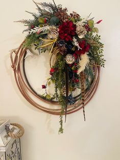 a wreath is hanging on the wall with flowers and feathers attached to it's sides