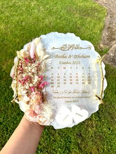 a person holding up a white plate with flowers on it in front of green grass