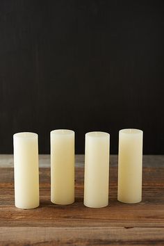 three white candles sitting on top of a wooden table