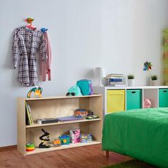 a child's bedroom with green bedding and toys on the shelf next to it