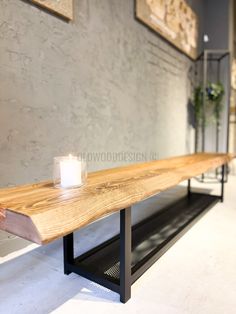 a candle is lit on a wooden bench in the middle of a room with concrete walls