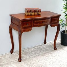 a wooden desk with two books on top and a potted plant next to it