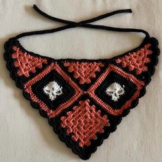 a black and red crocheted necklace with skulls on it