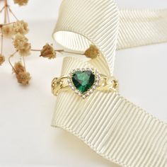 The love in your heart will sparkle with this one-of-a-kind emerald heart ring. Crafted from gleaming 14K yellow gold and set with a striking emerald gemstone cut into an intricate heart shape, this ring is a declaration of affection that will last forever. The emerald heart centerpiece catches the light from every angle, glowing a vivid green that symbolizes vitality, passion and eternal spring. Two sculpted gold bands intertwine below the emerald in a graceful heart shape, representing two souls joining together. Surprise the special woman in your life with this heartfelt gift and watch her eyes light up each time she glances down at this meaningful ring. This ring is the perfect romantic gift for a birthday, Valentine's Day or just because. Treat yourself or a loved one to a uniquely pe Green Heart Ring For May Birthstone, Fine Jewelry Style, Fine Jewelry Green Heart Ring For May Birthstone, Green Heart Ring For May Birthstone, Elegant Heart-shaped Green Emerald Ring, Elegant Green Heart-shaped Emerald Ring, Green Fine Jewelry Heart Ring For Wedding, Elegant Heart Shaped Emerald Ring For May Birthstone, Elegant Heart-shaped Emerald Ring For May Birthstone, Green Gemstone Heart Ring For May Birthstone