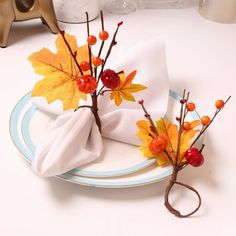 two napkins with autumn leaves and berries on them are sitting on a white plate