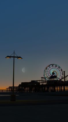 a ferris wheel sitting on top of a pier next to a light pole and street lamp