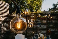 an outdoor dining area with hanging light bulbs