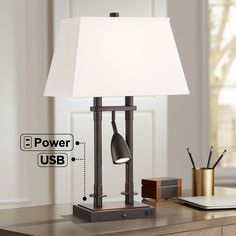 a desk lamp sitting on top of a wooden table next to a laptop and pen