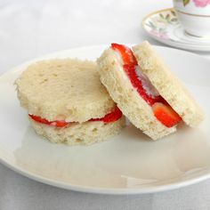 two biscuits with strawberries on them sitting on a plate next to a cup and saucer