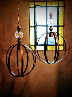 two circular lights hanging from the ceiling in front of a window with a stained glass pane