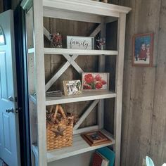 a white book shelf with pictures on the top and bottom shelves, in a room