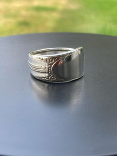 a silver ring sitting on top of a black table next to a green grass field