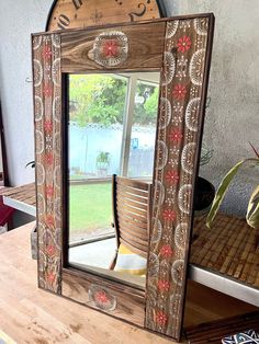 a mirror sitting on top of a wooden table next to a potted plant and window