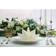 a white table setting with silverware and flowers in the backgroung area