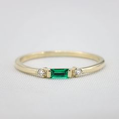 "Handmade by an inspired jewelry artist team with decades of experience in the craft of jewelry making. Each gemstone, each diamond is carefully picked. Using only the finest raw materials and the highest industry standard in manufacturing, design and finish. Sleek and sophisticated baguette Emerald and diamond ring. This rings dainty nature adds to its charm, the Emerald is elegantly set surrounded by two round diamonds adding to its slim design and elongating the ring. This dainty ring is perf Emerald Rings With Single Cut Diamonds For Anniversary, Emerald Rings With Single Cut Diamonds For Gifts, Dainty Emerald Cut Ring With Diamond Accents, Emerald Promise Ring With Single Cut Diamonds, Dainty Emerald Ring With Diamond, Round Emerald Ring With Single Cut Diamonds For Promise, Dainty Baguette Cut Birthstone Rings, Minimalist Emerald Diamond Ring For May Birthstone, 14k Gold Emerald Ring With Diamond Accents For Promise