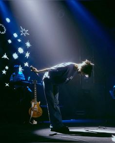 a man standing on top of a stage next to a guitar