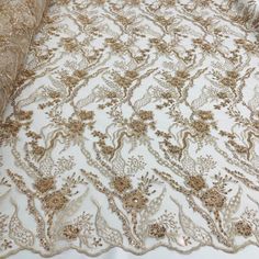 Dress up your special occasion with Lace USA's Beaded Lace Fabric Embroidered on 100% Polyester Net Mesh. This high-end, elegant fabric is perfect for making timeless beautiful couture lace pieces. Create a one-of-a-kind bridal lace, evening dress lace, quinceanera dress lace, or dance costume lace with decorative lace, beaded lace, and embellished lace crafted from this luxurious fabric. Showcase your creativity with our wedding dress lace and formal dress lace to make a statement that will las Gold Floral Embroidered Fabric For Ceremony, Elegant Beige Embroidered Fabric For Festive Occasions, Festive Lace Fabric With Pearl Embroidery, Festive Pearl Embroidered Lace Fabric, Elegant Festive Pearl Embroidered Fabric, Elegant Festive Lace With Floral Embroidery, Elegant Floral Embroidered Lace For Festive Occasions, Festive Elegant Lace With Floral Embroidery, Elegant Gold Embroidered Fabric For Ceremonies