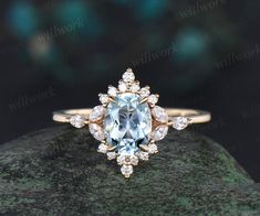 an aqua blue and white diamond ring on top of a rock