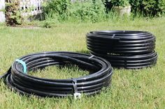 two black hoses laying in the grass next to each other