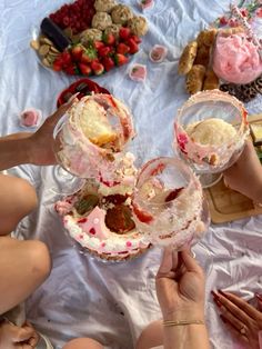 several people are sitting at a table with desserts and drinks in their hands,