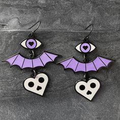 I designed these earrings with three levels of spookiness: eye, bat wing, and skull heart. 1.5 inch wide x 1.75 inch tall (49mm wide x 45mm tall) See coin photo for scale reference. Available in 2 color ways: Dark gray & white (does not glow), OR ✶Glow-in-the-dark✶ purple & white (the heart charm does not glow). The photo shows black ear hooks, but I'm now selling this with hypoallergenic steel ear hooks (perfect for sensitive ears). Modeled by Jaimee (in black), @soda_fontaine on Instag Emo Pierced Jewelry For Halloween, Emo Jewelry For Halloween Cosplay, Edgy Halloween Jewelry, Emo Metal Earrings For Halloween, Black Earrings For Halloween Cosplay, Black Halloween Cosplay Earrings, Gothic Plug Earrings For Halloween Gift, Gothic Halloween Plug Earrings As A Gift, Edgy Pierced Halloween Earrings