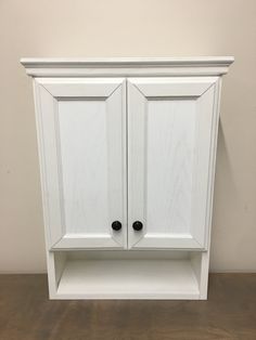 a white cabinet with two black knobs on it