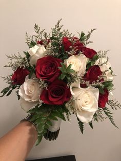 a bouquet of white and red roses in someone's hand